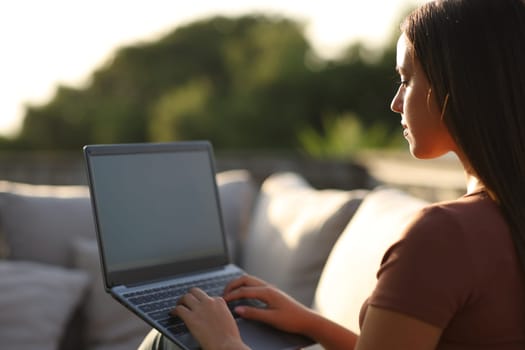 Woman using laptop in a terrace at home or hotel a sunny day