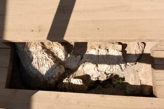 Exposed layers of stone and wooden beams reveal the ongoing excavation efforts at Knossos Palace, showcasing the contrast between ancient rock formations and modern restoration techniques.