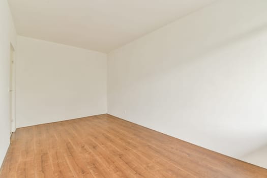 An empty room featuring a simple design with white walls and a wooden floor, providing a clean and spacious atmosphere for various uses.