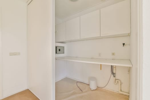 A clean and minimalist laundry room featuring white cabinetry and a simple layout. The design emphasizes functionality and simplicity, ideal for modern living.