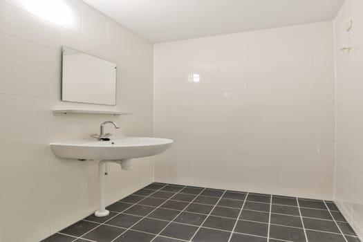 A clean and minimalist bathroom featuring a wall-mounted sink, a square mirror, and tiled flooring, creating a spacious and modern aesthetic.