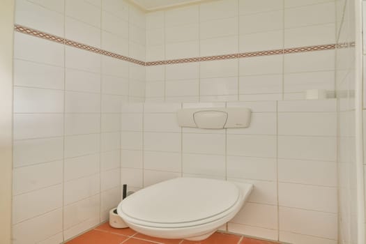 A clean and simple bathroom featuring a modern toilet against white tiled walls, accented with a subtle border design. Functional and uncluttered space.