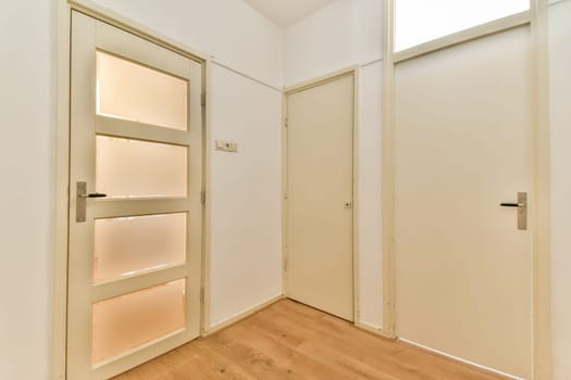 A contemporary hallway featuring two closed doors with a clean and minimalist aesthetic. The light wood flooring complements the neutral wall colors.
