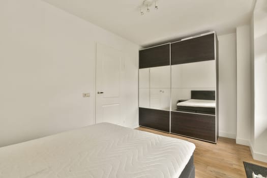 A minimalist bedroom featuring a sleek wardrobe and a simple bed layout. The neutral palette enhances the serene ambiance of the space.