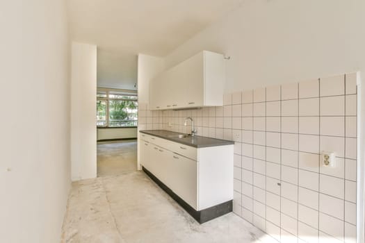 Spacious kitchen area featuring sleek cabinetry, simple countertops, and natural light streaming through large windows, creating a clean and airy atmosphere.