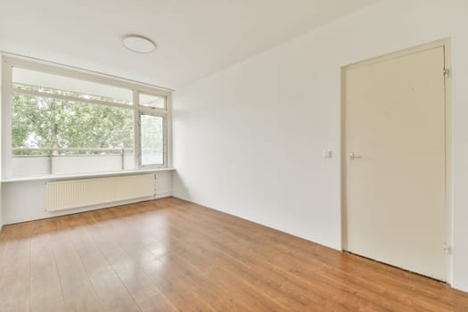 An airy room featuring large windows allowing natural light to illuminate the space, complemented by wooden flooring and a minimalist design.