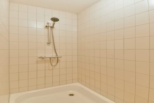 A clean and minimalistic shower area featuring pale tiled walls and a simple showerhead. The design emphasizes a fresh and spacious vibe.