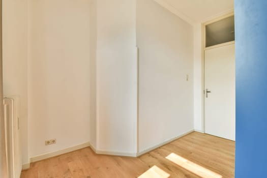 A spacious and bright minimalist room showcasing light walls and wooden flooring. Sunlight streams in, illuminating the simple design elements.