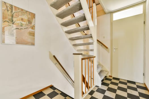 A sleek, modern staircase with a stylish design leading to an upper level, complemented by a piece of art on the wall, offering a contemporary interior look.