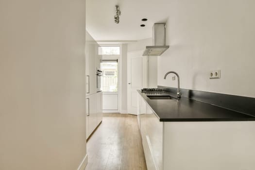 A sleek and modern kitchen showcasing a minimalist design with white cabinetry, a dark countertop, and ample natural light. Perfect for contemporary living.