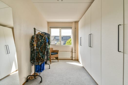 A modern dressing room featuring elegant clothing displays, ample storage space, and bright natural light streaming through the windows.