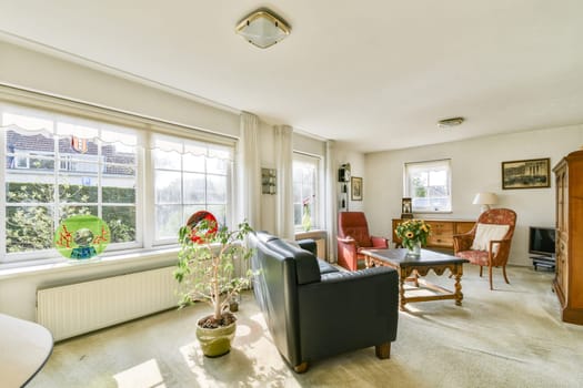 A cozy living room featuring plants, comfortable seating, and ample natural light, creating a warm and inviting atmosphere for relaxation and gatherings.
