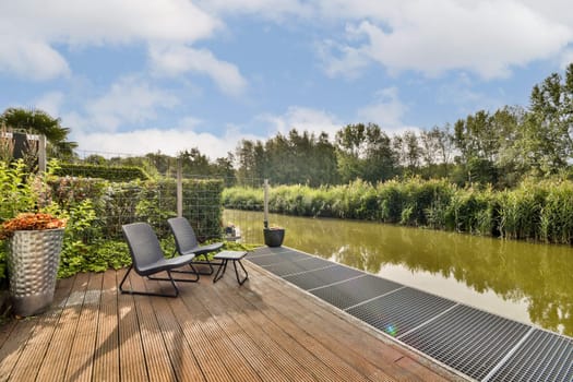 A peaceful riverside setting featuring comfortable seating, lush greenery, and tranquil water, perfect for relaxation and enjoying nature.