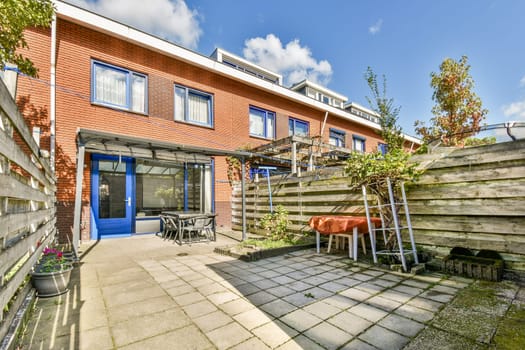 A contemporary urban garden featuring a clear blue sky, elegant patio area with furniture, and neatly arranged plants. Perfect for relaxing or outdoor gatherings.