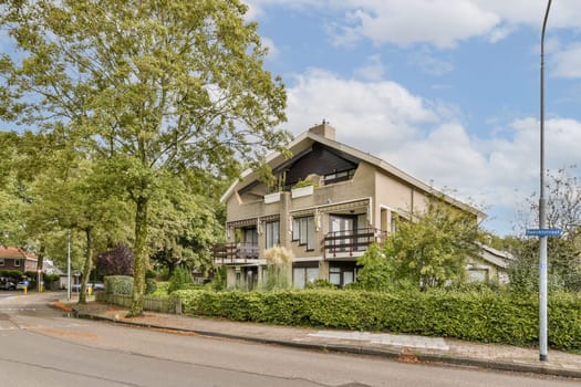 A picturesque view of a residential area featuring a modern house surrounded by lush greenery and trees, creating a serene atmosphere.