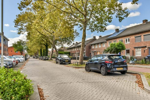 A picturesque view of a residential street lined with trees, showcasing parked cars and charming houses under a clear blue sky.
