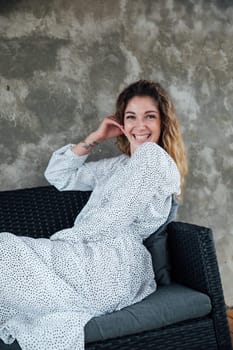 Fashionable woman in summer white dress smiling on gray background