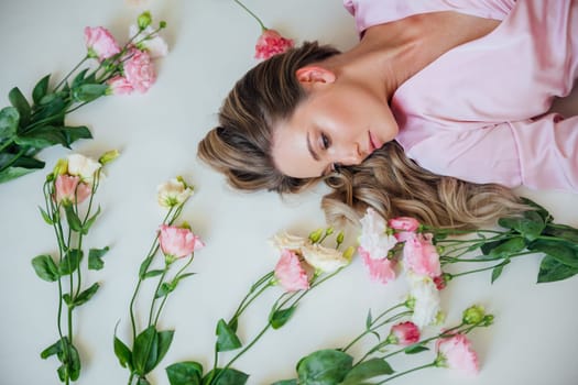 Fashionable woman in summer pink dress lying among flowers