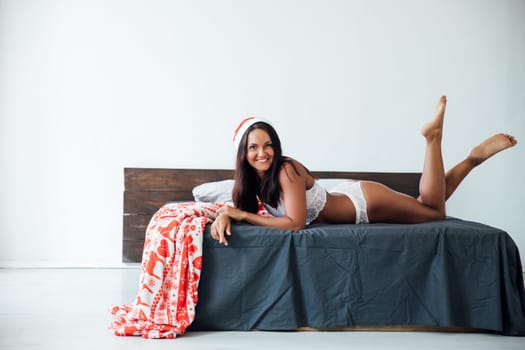 Woman in lingerie in hat in bedroom on bed for new year