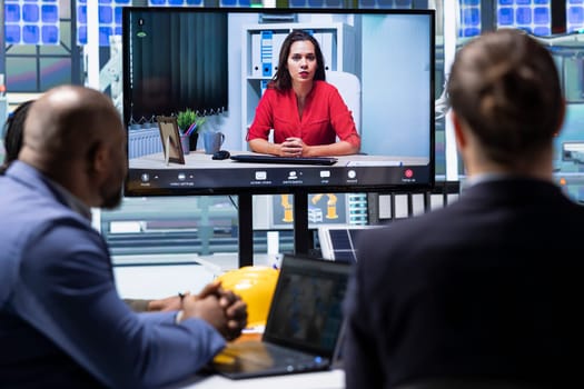 Compliance officer aids shareholders in assessing laws compliance during teleconference meeting. Investors in industrial plant examine financial statements and evaluate assets during online videocall
