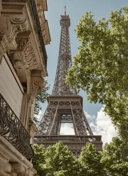 France, Paris - May 03, 2025 - The Ultimate Eiffel Tower View from on Rue de L’Universite in Paris. A back alley in Paris showcasing the architecture of Eiffel Tower view between with trees and typical parisian buildings in the foreground in Rue de l'Universite street, 7th arrondissement, use it as your Wallpaper, Poster and Space for text, Selective focus.