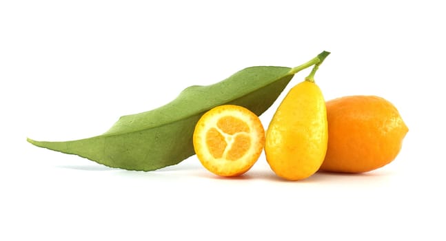 Two fresh kumquats resting on a white background, featuring one whole fruit with vibrant orange skin and a green leaf, alongside a half kumquat revealing its juicy pulp