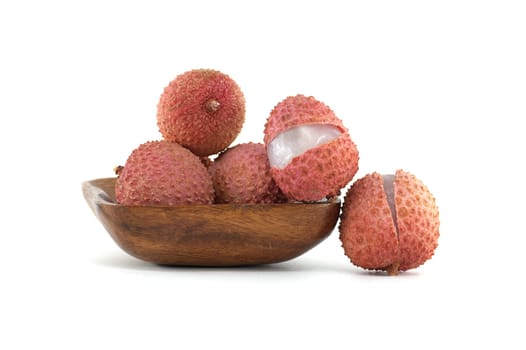 A display of fresh lychee fruits in a wooden bowl on a white backdrop. The fruits exhibit vibrant colors and textures, with one lychee open to reveal its juicy white flesh.