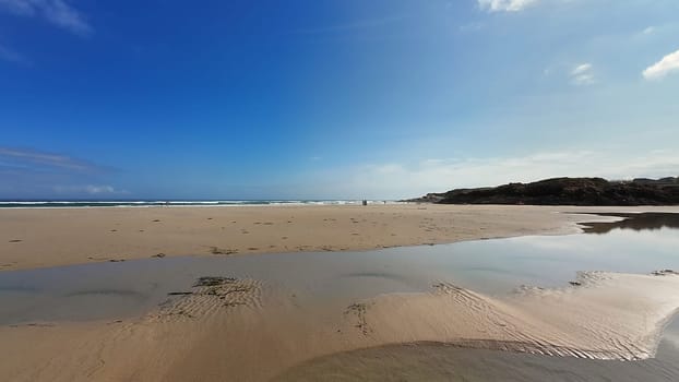 A beautifully tranquil beach scene featuring soft white sand, stunning reflections, and a vibrant blue sky above