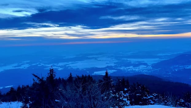 Experience a breathtaking view of an expansive snowy landscape illuminated under a vibrant twilight sky