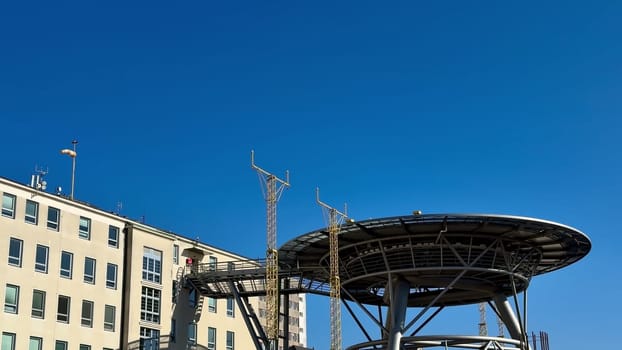 A contemporary communication tower setup is placed adjacent to a building beneath a bright and clear blue sky