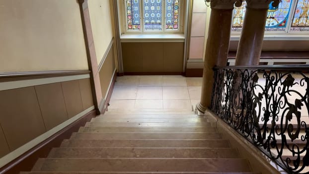 This beautiful and stunning staircase showcases intricate architecture adorned with magnificent stained glass windows