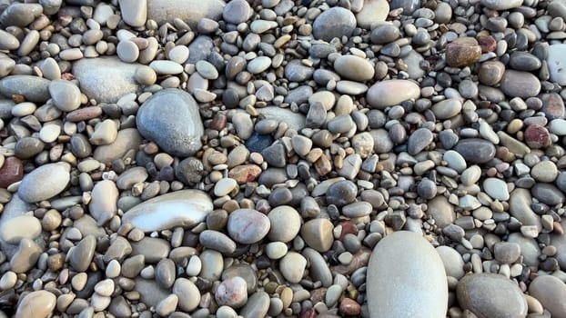 A picturesque view of a pebbled beach, with calm waves lapping gently and stones scattered across the shore