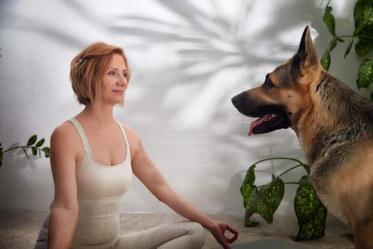 Engaging in a yoga session surrounded by plants while a dog relaxes nearby evokes a calm and healthy lifestyle.