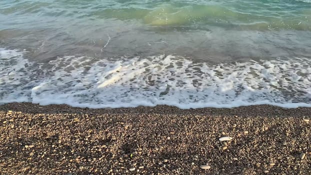 Capture the serene and stunning beauty of ocean waves as they gently wash onto a lovely pebbly shore