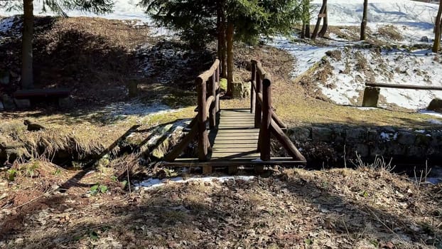 A quaint little wooden bridge is nestled in a serene snowy forest, making it perfect for leisurely winter strolls