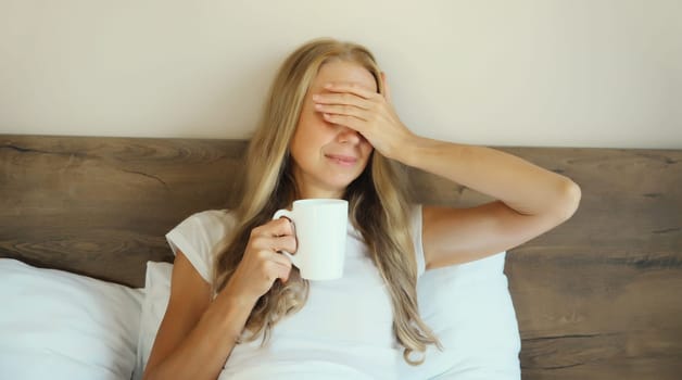Tired woman waking up after sleeping on monday holding cup of coffee drink, touching head, suffering from headache, stress, fatigue, migraine lying on the pillow in white bed in bedroom at home