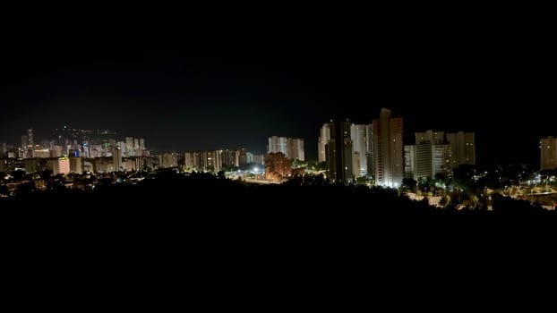 A stunning panoramic view of a city skyline at night, showcasing illuminated buildings and vibrant lights.