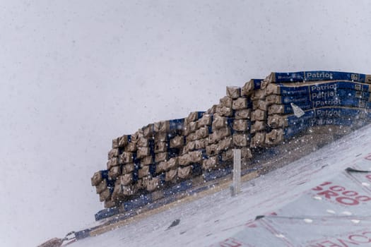 Georgetown, TX - 5 May 2025: Stack of Patriot shingles on roof of new home during thunderstorm with severe hailstones