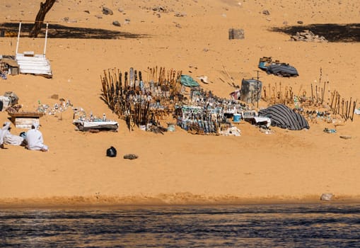 Collection of Egyptian gifts and trinkets on the sandy beach by Nile River in the Nubian village near Aswan