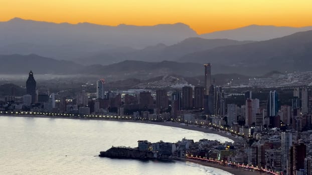 A stunning sunset lit up the skyline, reflecting on calm waters with majestic mountains in the background