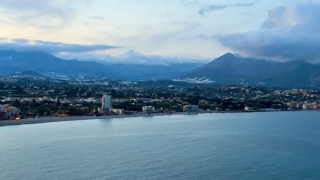 A beautifully peaceful seaside landscape showcasing majestic mountains, gentle waves, and a serene tranquil sky