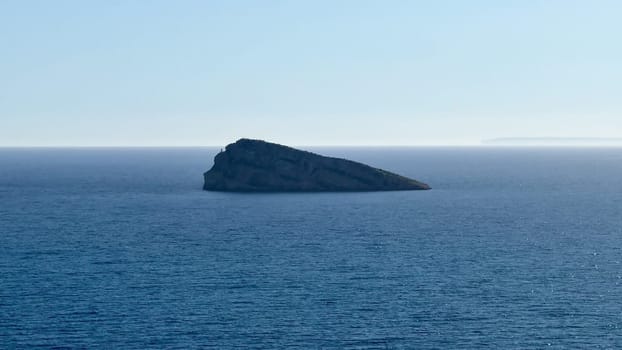 A tranquil view of the vast ocean, with a solitary rock on the horizon, illustrating natures beauty and serenity