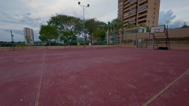 A large and spacious outdoor basketball court is beautifully surrounded by several modern apartment buildings