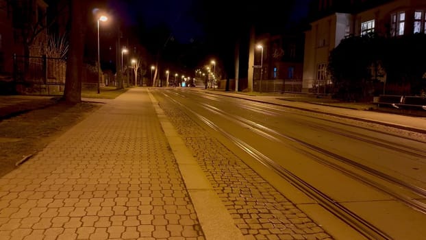 A serene, deserted street in the dead of night, showcasing softly glowing street lamps and distinct tram tracks