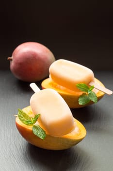 Enjoying creamy mango ice cream nestled in halved ripe mangoes, garnished with fresh mint leaves, ideal for a refreshing snack or dessert on a hot day