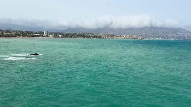 The view is breathtaking, with turquoise waters, a charming town, and majestic mountains under a clear sky
