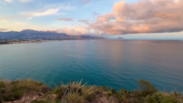 A breathtaking coastal view presents serene, calming waters and vibrant, colorful clouds during a stunning sunset