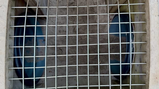 This image shows a closeup of a drainage grate with blue inlets for efficient water flow management