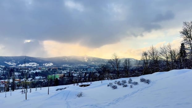 Bright sky at sunset over snow-capped mountains and the city of Liberec. High quality 4k footage