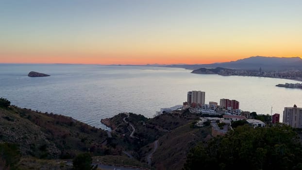 A breathtaking sunset that beautifully illuminates the coastal skyline, casting stunning reflections on the calm water
